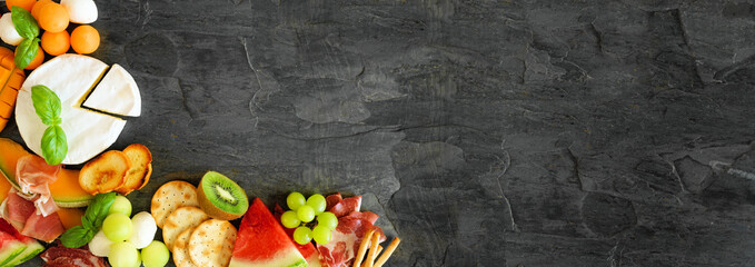 Summer fruit theme charcuterie corner border against a dark slate background. Selection of fruits,...