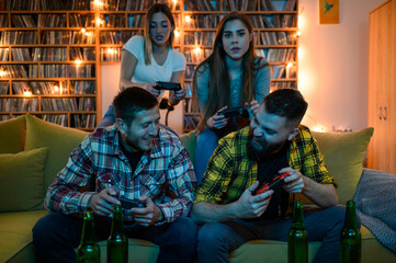 Fototapeta na wymiar Group of friends playing video games and holding consoles while sitting on the couch