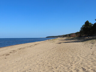 Baltic sea and sandy beach: blue sky and sea, white waves, yellow sand as copy space