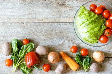 Bowl of organic and bio fresh vegetables tomato, peppers, potato, carrots lies on rustic wooden background table with copy space. Healthy natural ripe vegetarian vegetables concept. Salad ingredients