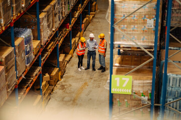 Manager with workers controlling stock in factory warehouse