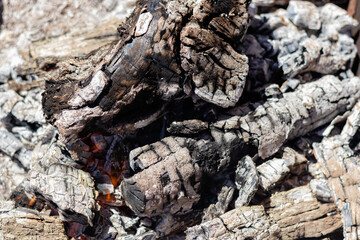 The texture of hot coals, embers and ashes left over from the burned wood, but which still burns smoldering with flame and smoke