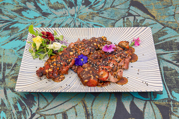 Very elaborate recipe of duck stew with sesame seeds, poppies, edible flowers and sauce