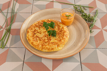 Spanish omelette for one person with a side of salmorejo, with rosemary, chives and parsley