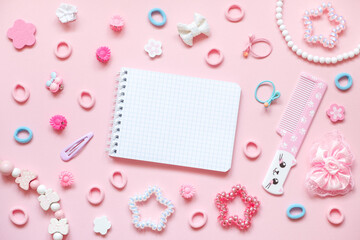 Blank notepad, cute comb with kawaii cat face and kid's hair accessories on pink pastel background