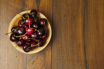 Red fresh juice cherry in a wooden bowl on a wooden table. Fresh berries. Food industry. Produce product