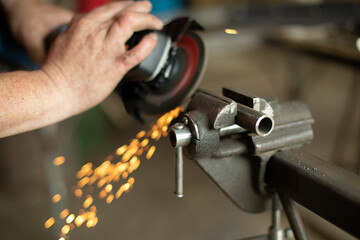 A man is working on a part in the garage.Metal grinding. Steel processing with power tools.