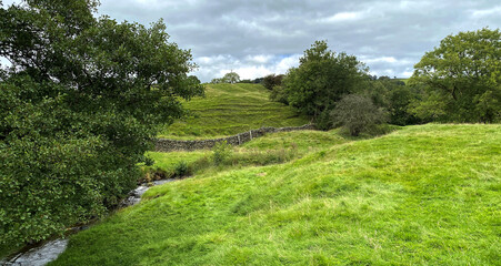 Rural landscape, with fields, a dry stone wall, and a stream, on a cloudy day near, Silsden, Keighley, UK