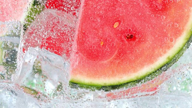 Super Slow Motion Shot of Bubbling Water with Melon Slices and Ice Cubes in Glass at 1000 fps.