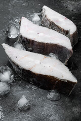 Frozen halibut steak, on black dark stone table background