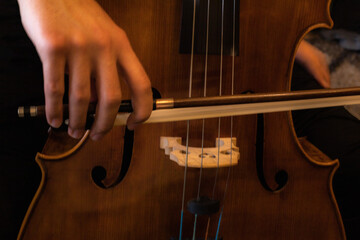 detail of a hand holding a music bow to play a cello and to bring out the sound