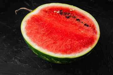 A half of fresh watermelon, on black dark stone table background