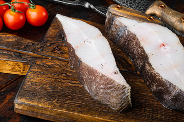 Piece of fresh raw halibut fish, with ingredients and rosemary herbs, on old dark  wooden table...
