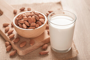 Glass of almond milk and almonds on table