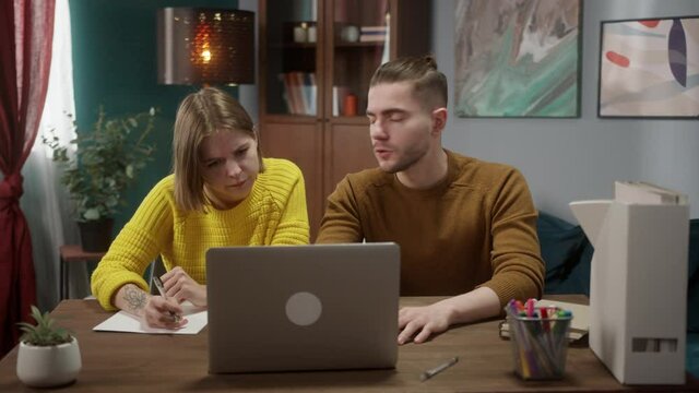 Young Couple staying at home using laptop computer for attending online course together, man and woman talking and learning new skills about healthy food or language, remote video lesson or work