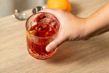 Close-up view of negroni cocktail being lifted by one hand