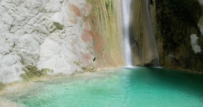 Close up of small waterfall ending up into natural pool with turquoise blue water.