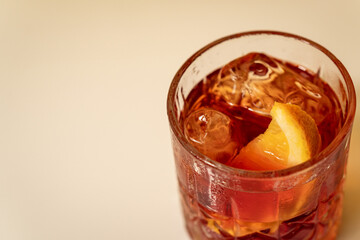 Close-up view of negroni cocktail with orange wedge on white surface