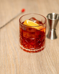 Front view of the preparation of a negroni with mixing spoon and jigger
