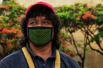 Latino man with cap and mask looking sideways