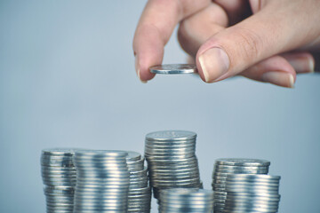 Hand put silver money coins to one of stacks. Concept of business planning and finance. Expenses and earnings. Different growth of infographics. Alms and donations. Small savings.