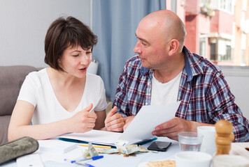 Portrait of family couple with financial documents and money at kitchen table