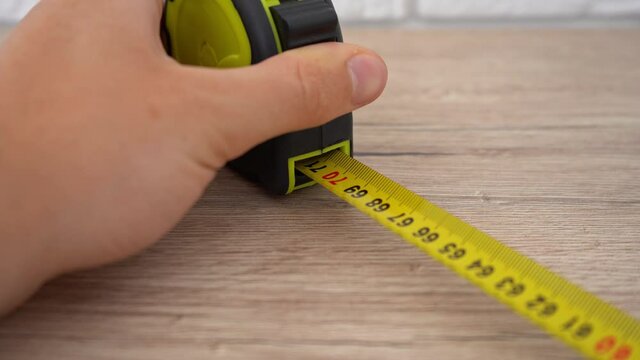 Measuring with yellow tape measure. Hands pull the measuring tape out of tape measure and measure the length. 4k stock footage.
