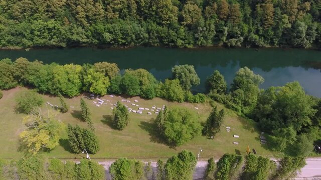 A drone flight over a scenic view of an ancient graveyard and a river and main road that follows its course.