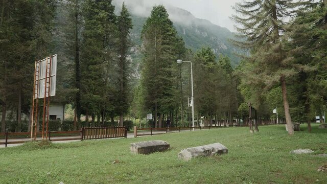 An old ancient graveyard in the scenic mountain town having trees and grass and the main road that follows its course.