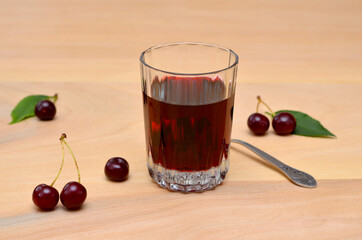 glass with berry wine and cherries on the table