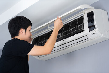 man open the air conditioner indoor at home