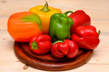 fresh colorful bell peppers on wooden board