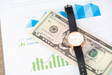 Watch and dollar bills on financial documents