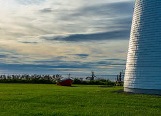 small boat next to lighthouse base at with low sun