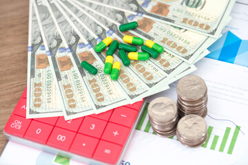 Scattered capsule medicines on dollar bills with calculator and coins