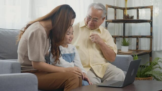 Happy family senior grandfather, daughter and granddaughter talking online via video chat using laptop computer with father, old grandpa embracing little grand child and mother in living room at home