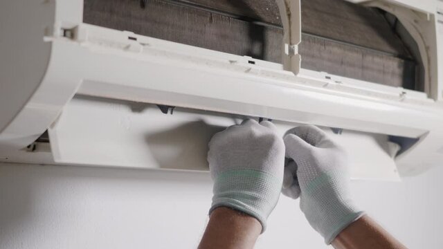 Technician service checking and repair air conditioner house indoors on the wall, young man electrician maintenance he remove air conditioning to fix problem