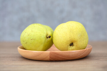 Two green pears in a wooden dish