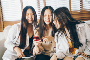 Obraz premium Beautiful asian women use smartphone social media together sitting on sofa