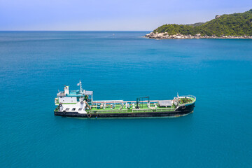 Small green container ship on a blue sea ocean no people and copy space aerial ariel drone uav view 