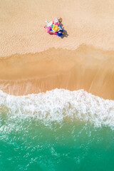 Inflatable toy seller on the beach drone aerial ariel uav top down birds eye view of beach scene sunny happy copy space and no people yellow sand green sea waves crash - obrazy, fototapety, plakaty