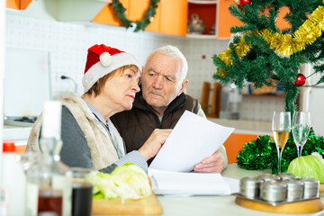 Image of aged family trying to pay utility bills before new year dinner