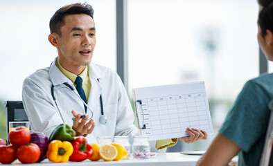 Friendly Asian nutritionist showing table to patient