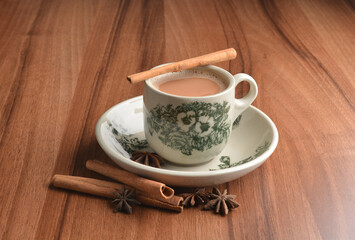 hot masala chai milk tea in traditional ceramic cup with cinnamon and star anise on wood table hot healthy asian beverage menu 