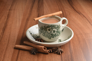hot masala chai milk tea in traditional ceramic cup with cinnamon and star anise on wood table hot healthy asian beverage menu 