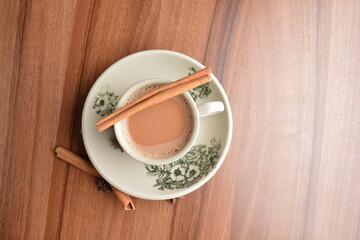 hot masala chai milk tea in traditional ceramic cup with cinnamon and star anise on wood table hot healthy asian beverage menu 