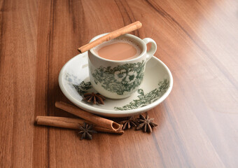 hot masala chai milk tea in traditional ceramic cup with cinnamon and star anise on wood table hot healthy asian beverage menu 