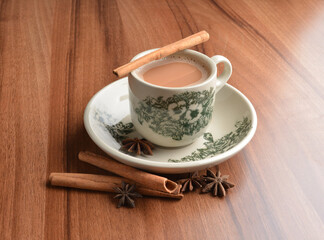 hot masala chai milk tea in traditional ceramic cup with cinnamon and star anise on wood table hot healthy asian beverage menu 