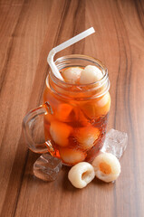 cold lychee longan fruit ice tea kombucha with white straw on wood table cocktail chilled beverage...