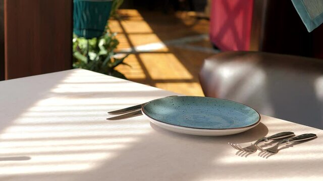 Table setting in an elite restaurant close-up. Men's hands arrange beautiful clean and empty glass glasses and plates. Decorative tableware and a candle holder. The waiter sets the table